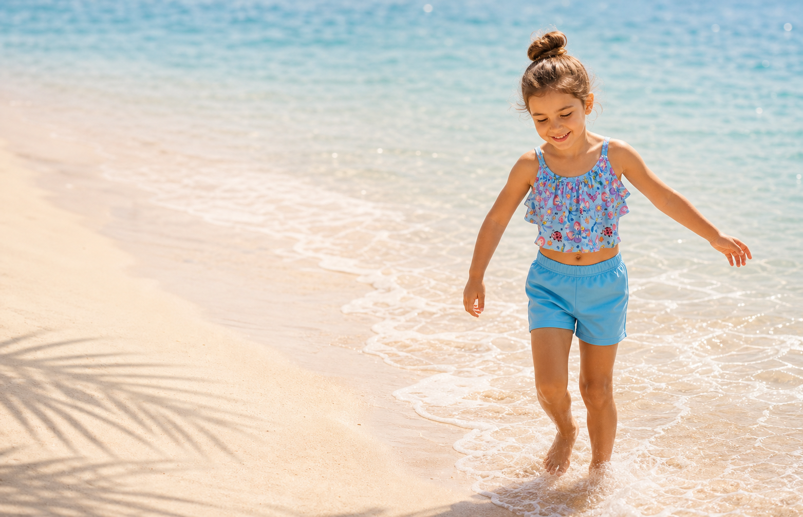 Niña caminando en la playa con conjunto celeste de ropa de baño